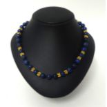 A lapis lazuli bead and gold necklace, composed of 60 uniform beads of 8 mm diameter, with