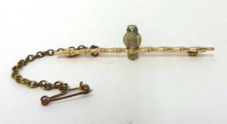 A Victorian 9ct two colour gold bar brooch, composed of an owl with green glass eyes on a branch,