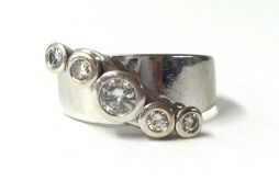 A white metal five stone diamond ring, collet set with graduated brilliant cut stones, approximately