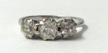 A white metal three stone diamond ring, claw set with graduated old cut stones, total weight