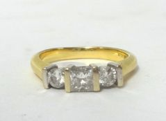 An 18ct gold three stone diamond ring, claw set with a Princess cut stone weighing approximately 0.
