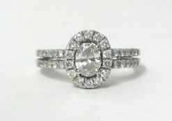 An 18ct white gold and diamond cluster ring, claw set with an oval cut stone of approximately 0.