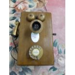 A wall-mounting telephone with oak case, brass finger dial and ear piece, the case stamped 4101AJ