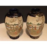 Pair of blue ground ovoid Satsuma vases each with two panels enamelled with figures in landscapes,
