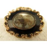An early Victorian large oval memorial brooch with gold scrolled edge, the locks of hair entwined