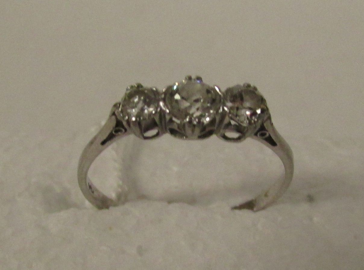 Three stone diamond ring on white metal shank stamped PLAT, largest stone estimated at 0.3 carats