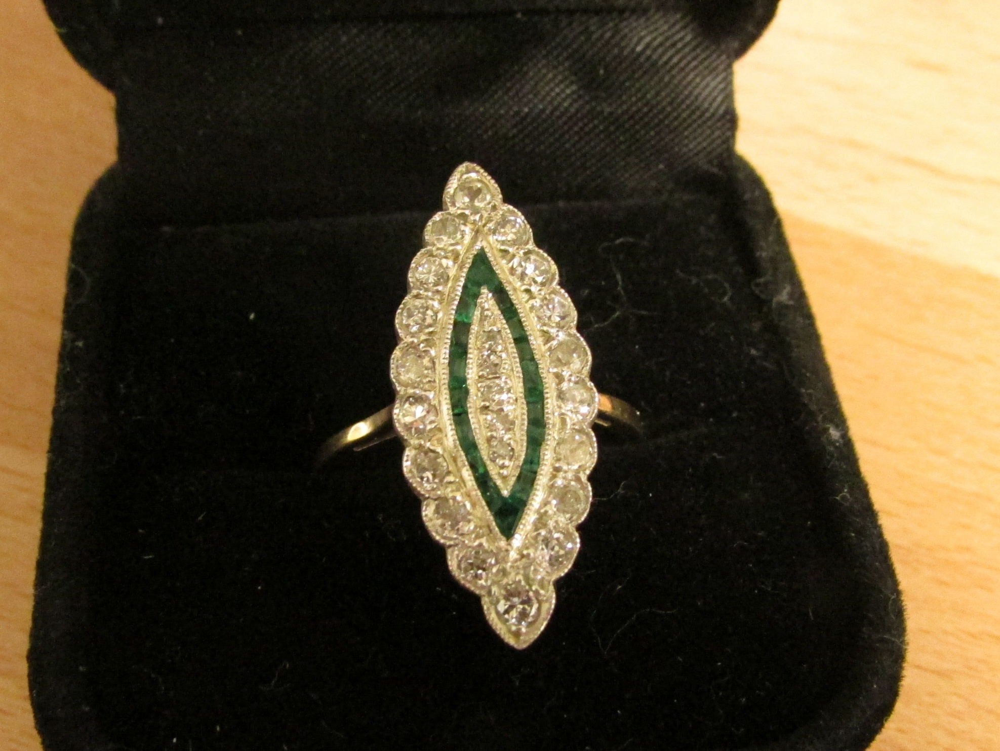 Diamond and emerald ring in a marquise setting (25mm x 10mm), perimeter of eighteen diamonds (