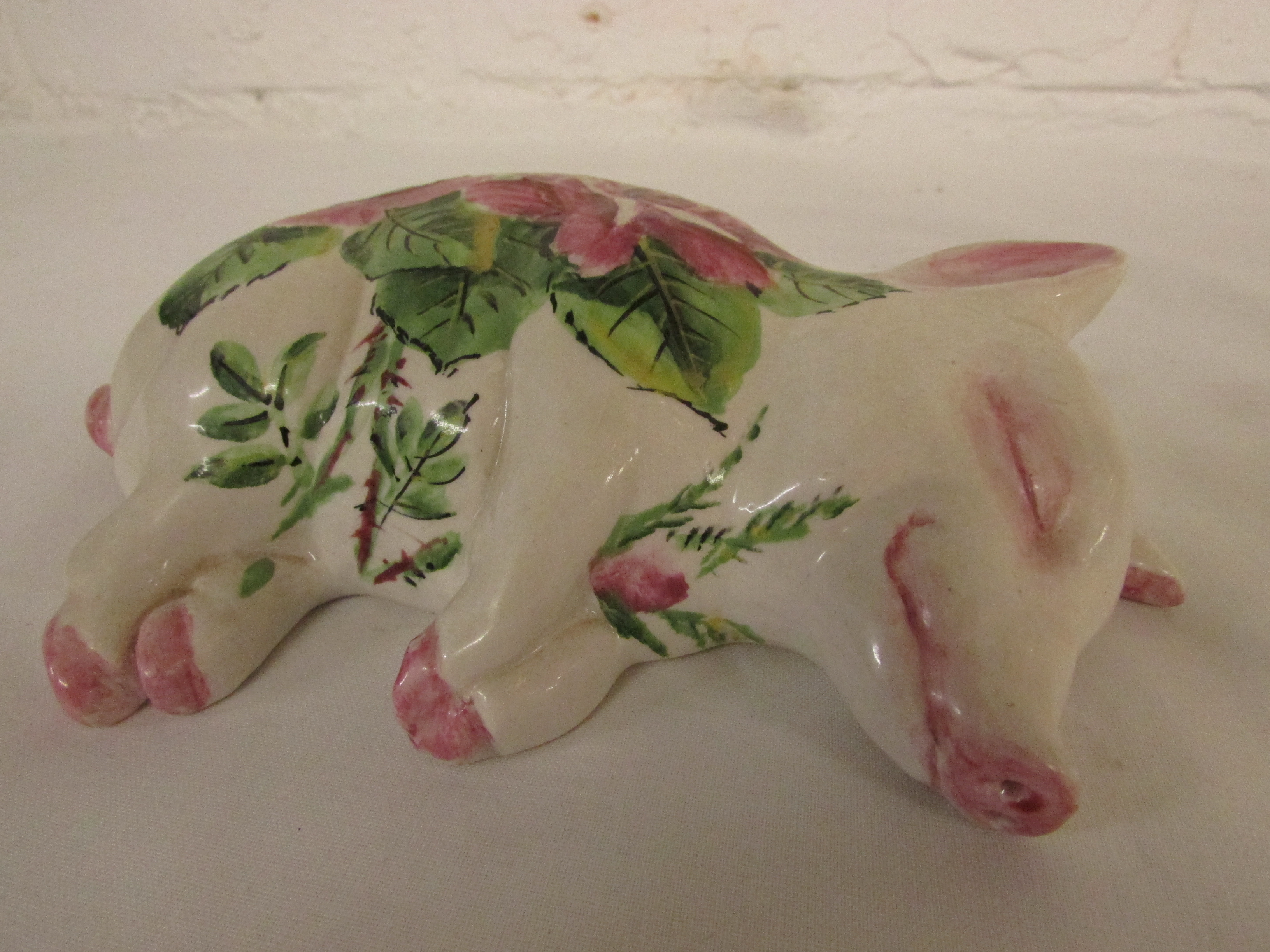 Exon Pottery Wemyss Ware Brian Adams figure of a sleeping pig, painted with pink roses and green