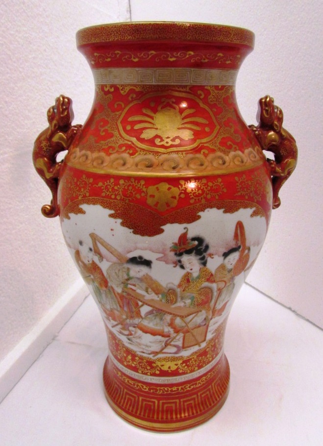 A Japanese porcelain baluster vase moulded with two dogs at the shoulder, red ground and gilding,