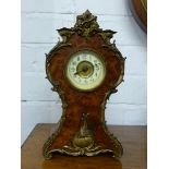 A waisted Rococo style mantle clock with applied brass mouldings, the mahogany frame with  stained