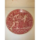 Pottery dish decorated in red lustrous glaze with robed woman and cherub before tree, in the style