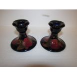 Pair of initialled Moorcroft pottery short candlesticks, pomegranate on dark blue ground, stamped