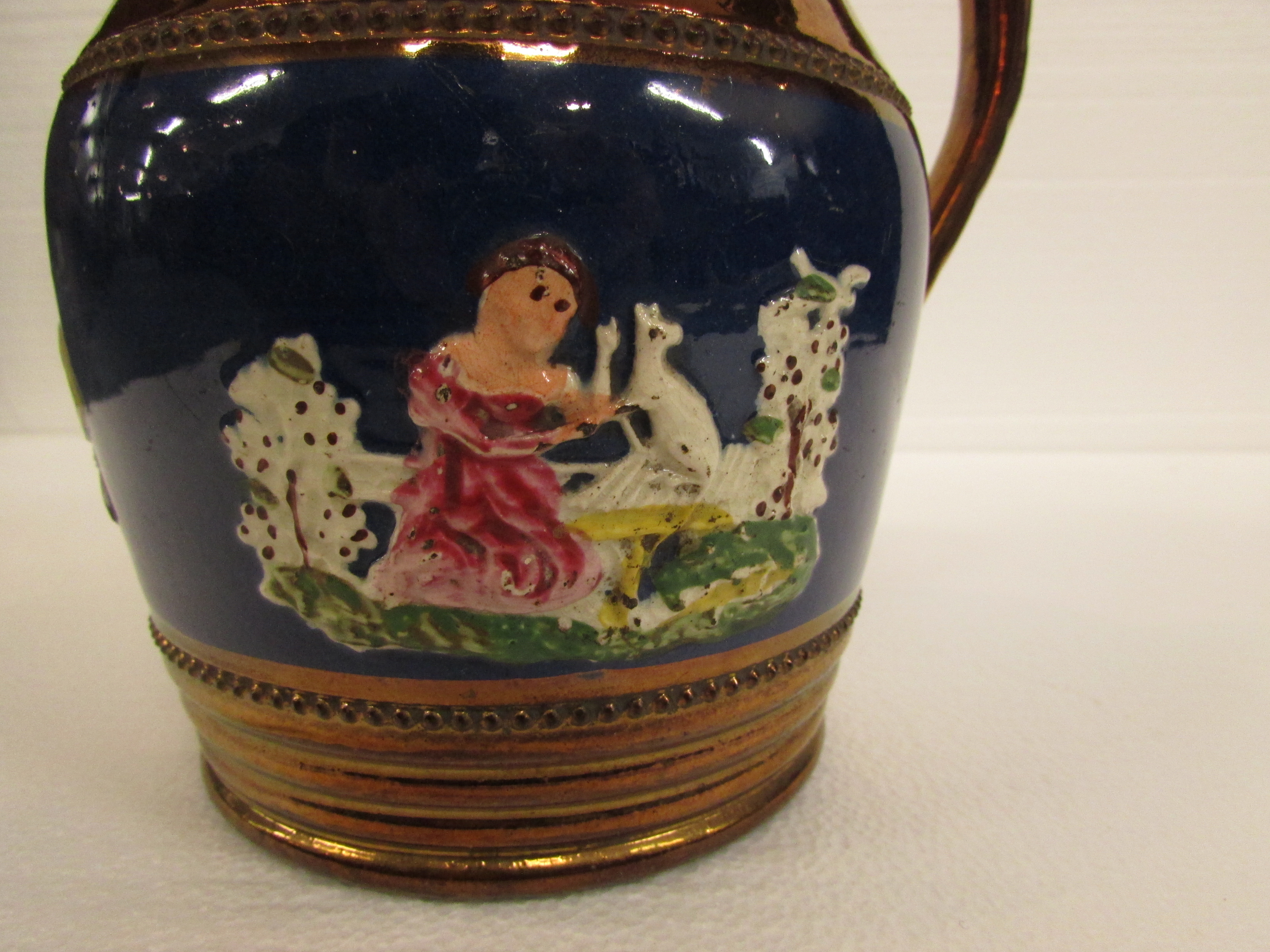 A 19th century copper lustre jug with a band of blue glaze with seated girl and dog in relief - Image 2 of 4