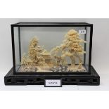 Large Chinese cork carving of landscape scene with pagoda, in a glass case on carved stand,