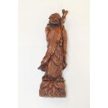 Chinese carved hardwood figure of a robed man holding a staff, standing on naturalistic base,