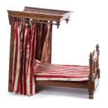 Miniature half tester bed with turned pillars and scroll decorated foot board,