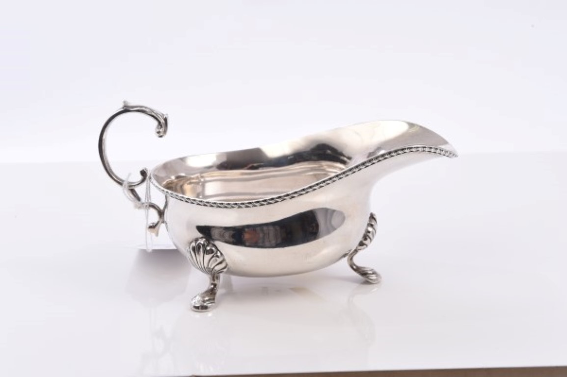 1920s silver sauce boat of conventional form, with gadrooned border and open scroll handle,