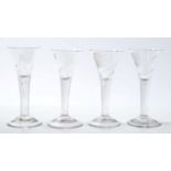 Set of four Georgian wine glasses with trumpet-shaped bowls, each engraved with flower and insect,