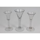 Three Georgian wine glasses with trumpet-shaped bowls, plain stems,