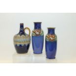 Pair of Royal Doulton stoneware vases with tube-lined floral and foliate decoration on blue