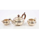 George V silver three piece bachelor tea set comprising teapot of compressed form,