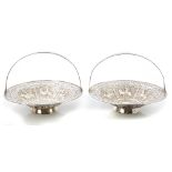 Pair Indian silver swing-handled cake baskets with pierced foliate borders and decorative embossed