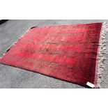 An Afghan rug with three rows of seven guls and repeat geometric borders, black on deep red ground -