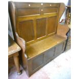 A 4' 2" polished oak settle with panelled back, shaped sides and locker seat