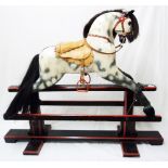 A mid 20th Century dapple grey rocking horse with horse hair mane and tan leather saddle, set on