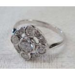 An unmarked 18ct. white gold ring, set with central diamond, four opposing stones and smaller stones