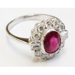 An 18ct. white gold ring, set with central oval ruby, within a diamond border with flanking baguette