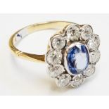 An 18ct. gold flowerhead ring, set with central oval sapphire within a ten stone diamond border (1.