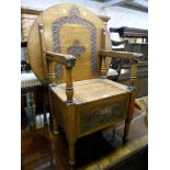 An early 20th Century oak monk's chair with circular table top, repeat carved motif decoration,