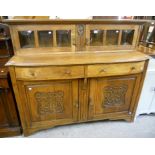 A 5' early 20th Century oak sideboard, the raised top section enclosed by a pair of cushion glazed