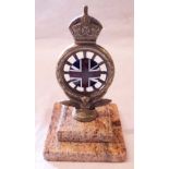 A brass car mascot of a crowned wheel held by a winged figure, with central enamelled Union Flag (