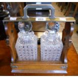 An oak and silver plated tantalus, with two hobnail cut glass decanters and Betjemanns patent