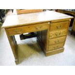 A 3' 6" early 20th Century oak single pedestal desk, with single frieze drawer, flight of four