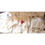 A collection of antique and vintage clothing, including Red Cross cap and apron, other aprons,