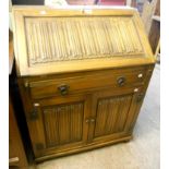 An Old Charm polished oak bureau, with linen fold decoration to fall and panelled cupboard doors