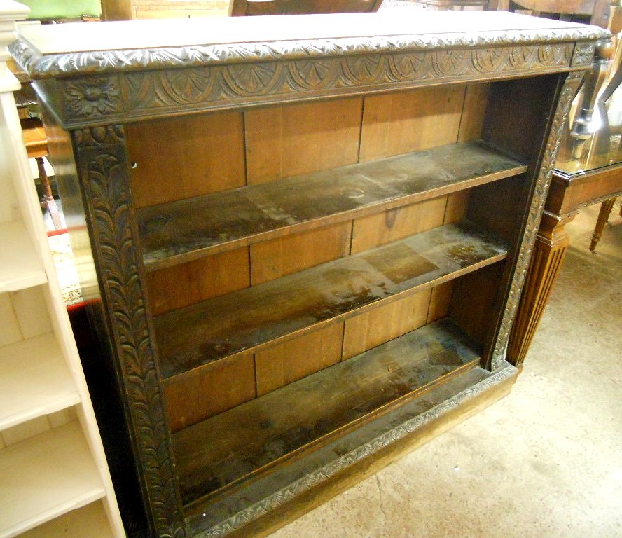 A 4' Victorian oak bookcase with carved decoration and four adjustable shelves, set on plinth base