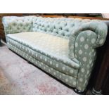 A 7' Chesterfield settee upholstered in frosted green button back material, set on bun feet