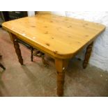 A 4' modern varnished pine kitchen table with thick top, set on turned legs