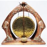 An Art Nouveau hammered copper gong stand with stylised floral decoration and faceted beater, with a