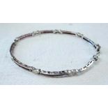 A 9ct. white gold curved panel bracelet, set with rows of rubies and small diamond to each of the