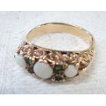 A 9ct. gold ring set with three opals interspersed with four small emerald chips