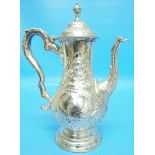 An 18th Century silver coffee pot of slender baluster design, with flip top and embossed C-scroll