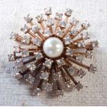 An unmarked gold retro style starburst pattern brooch, set with central pearl and numerous