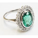 An 18ct. white gold ring, set with central oval emerald (2.35ct.) within a a diamond set border