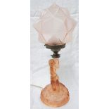 An Art Deco pink glass table lamp in the form of a kneeling lady holding a torch, with frosted