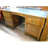 A 4' 7" mid 20th Century oak twin pedestal desk, with flanking slides, drawers and tilting file
